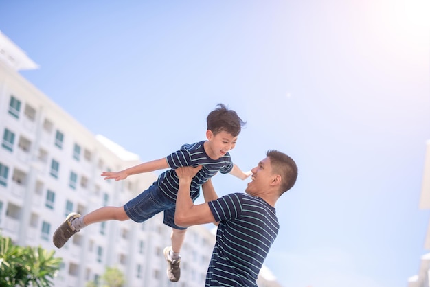 空に向かって街に立っている間に息子を背負っている父親