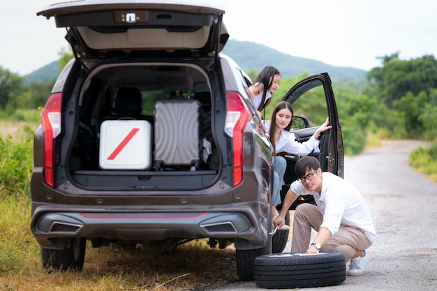 父はタイヤを交換し、彼の家族は旅行の間に待っています