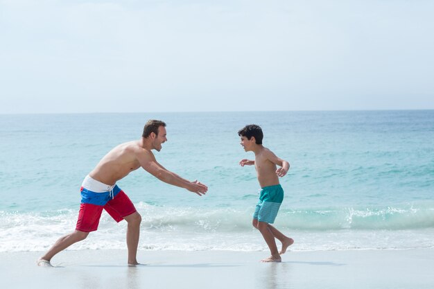 Father chasing son at beach 