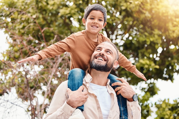 Father child and happy back ride in nature for family bonding time summer break or holiday together outdoors Happy dad carrying son on piggyback with smile enjoying vacation in the park outside