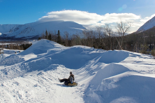 父と子は山からスノーチュービングに乗ります。凍るような澄んだ雪の日の冬の楽しみ。共同家族休暇