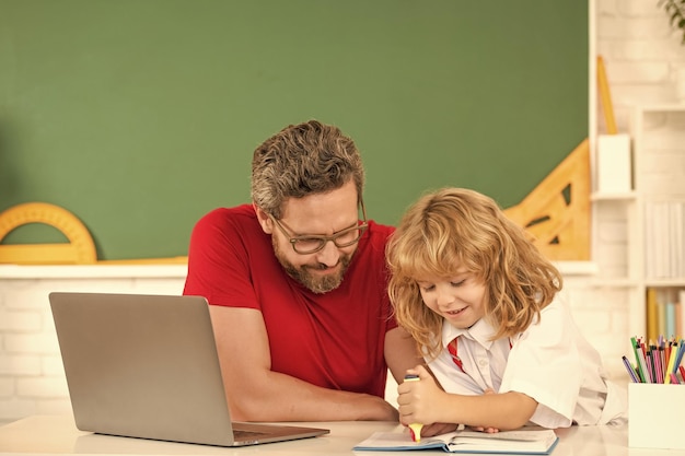 Отец и ребенок учатся в классе со знаниями ноутбука