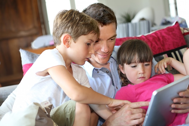 父と子供たちが自宅でタブレットで遊んで