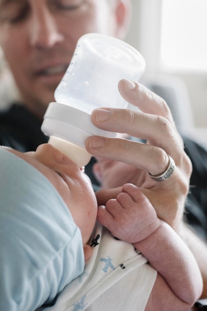 Un padre che culla un bambino piccolo e lo allatta con il biberon