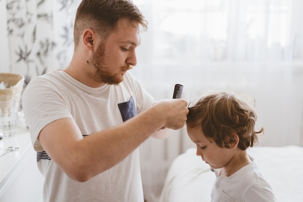 Father cuts her son hair in the room. Family during quarantine