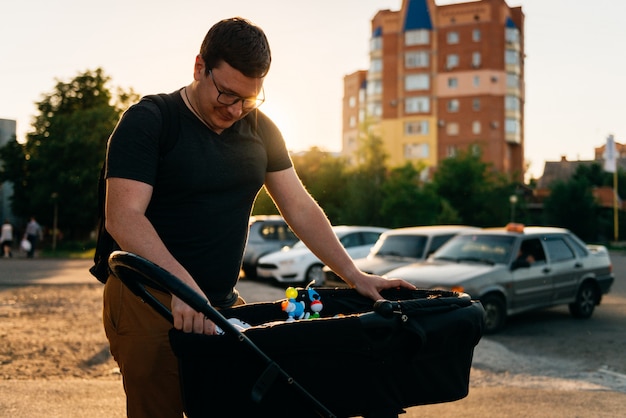 Father dad with newborn pram stroller outside during summer evening sunset