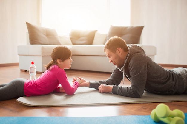 Father and daughter are training at home. Workout in the apartment.