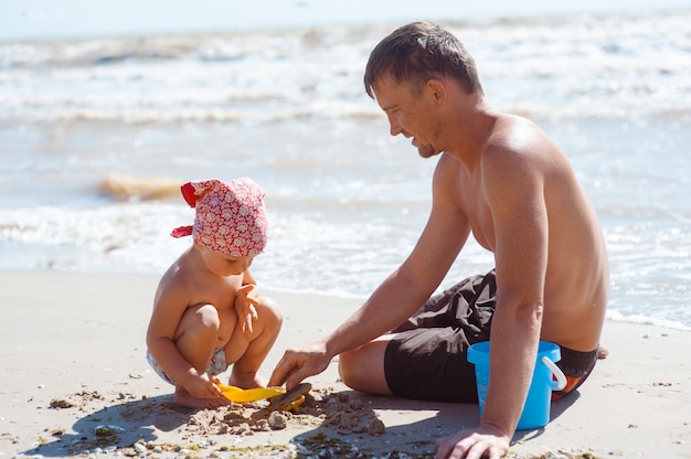 Father and daughter on beach playing and building sand castle