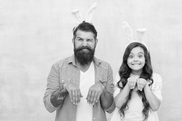 Father and daughter in bunny ears hunting colorful eggs Easter day Modern Family preparing for Easter happy easter funny dad and child girl wearing bunny ears egg hunt concept copy space