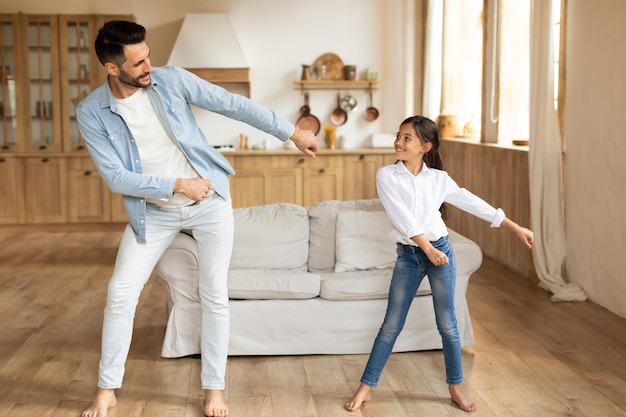 Father and daughter dancing in living room