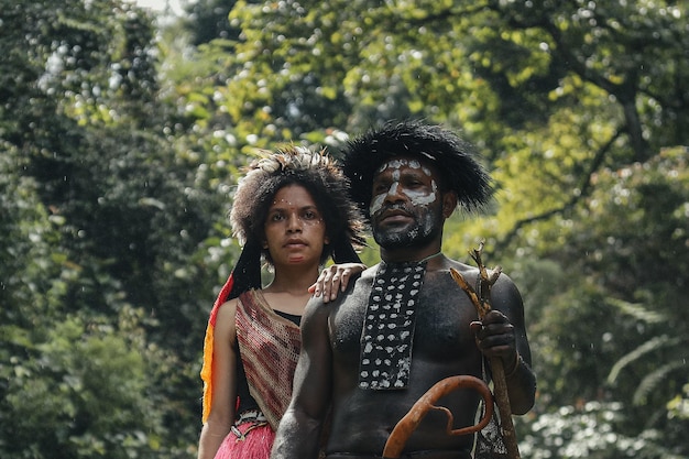 Father and daughter of Dani tribe in traditional clothes standing together at greenery forest Papua