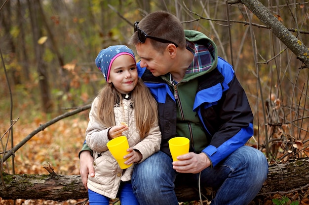 Father and daughter drinking tea in the autumn forest