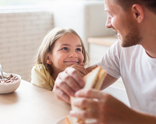 Photo father and daughter eating together