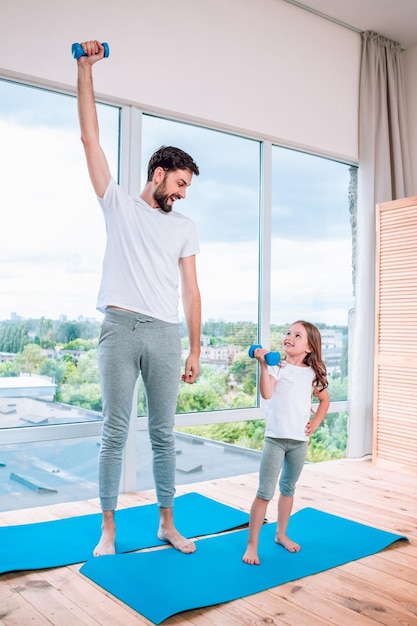 Father and daughter exercising at home using dumbbells