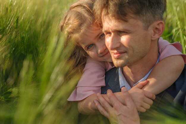 Foto padre e figlia in un campo di grano verde. avvicinamento. concentrati sulla ragazza.