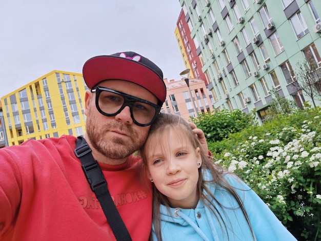 Father and daughter handsome young man and little cute girl\
make funny selfie on smartphone at home have fun dad and child\
laugh father\'s day