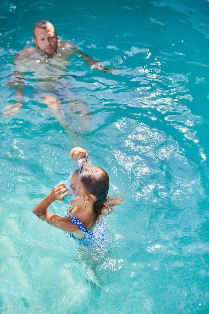 Father and daughter have fun in swimpool at home