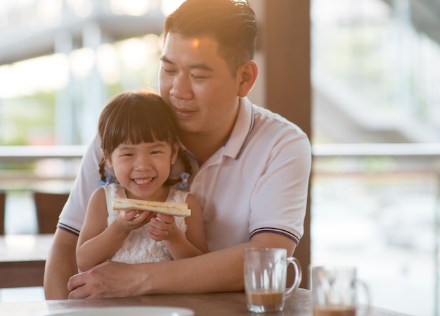 father and daughter having breakfast at table in restaurant