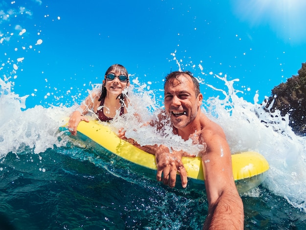 Father and daughter having fun on the beach while floating on airbed