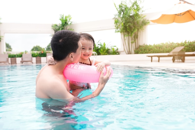 Father and daughter having fun in the pool. Summer holidays and vacation concept