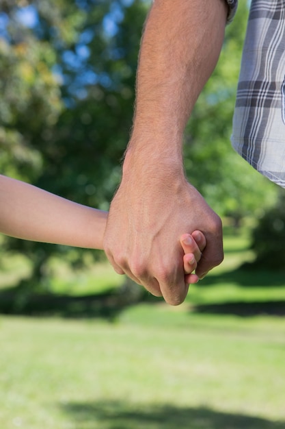 Foto padre e figlia che si tengono per mano nel parco