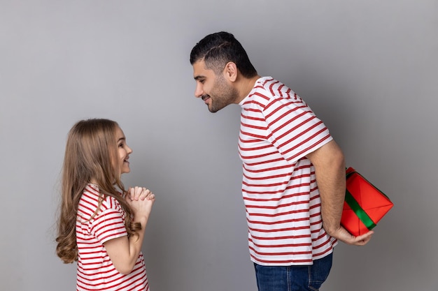 Padre e figlia che nascondono la confezione regalo dietro la schiena bambina che aspetta il suo regalo