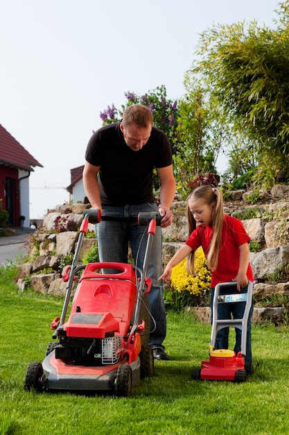 Father and daughter mowing lawn together