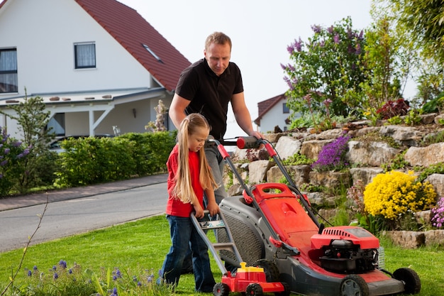 Father and daughter mowing lawn together