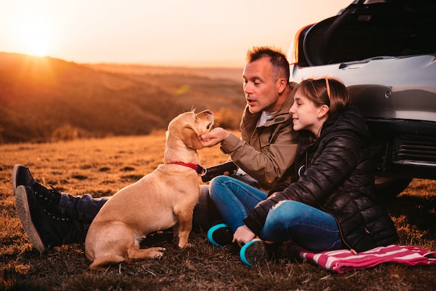 Father and daughter petting a dog on camping at hill