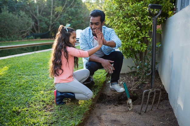 Father and daughter planting a tree in garden at backyard