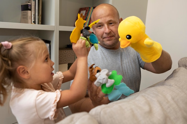 Foto padre e figlia che giocano con simpatici pupazzi