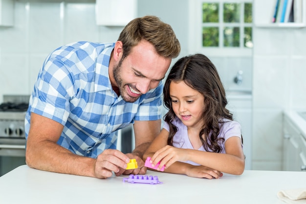 Отец и дочь играют с игрушечным блоком за столом