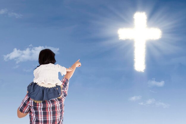 Father and daughter pointing at cross