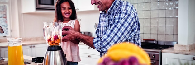 Father and daughter preparing smoothie in kitchen