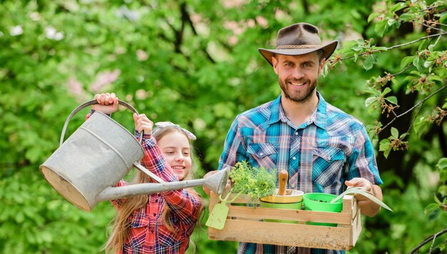 Father and daughter on ranch little girl and happy man dad
earth day spring village country ecology watering can and shovel
family farm working in greenhouse florist at work