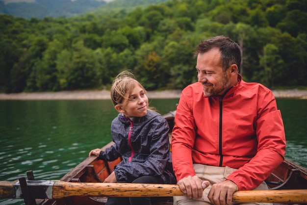 Father and daughter rowing a boat on the lake