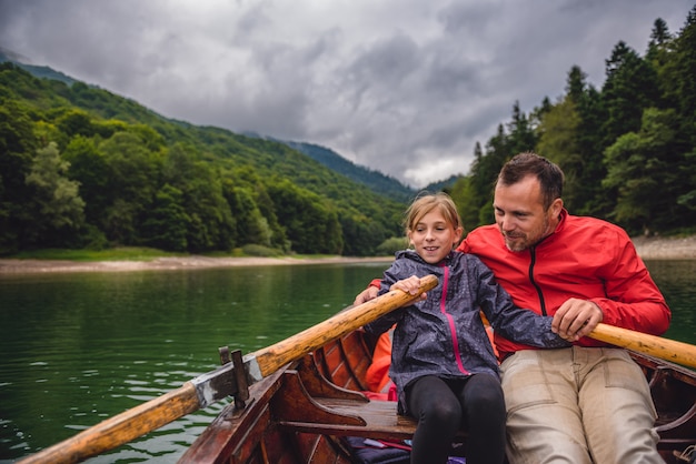 Father and daughter rowing a boat on the lake