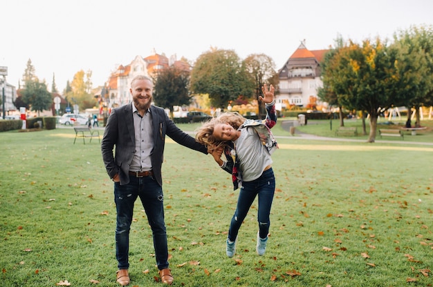 Photo father and daughter running on the grass in the old town of austria