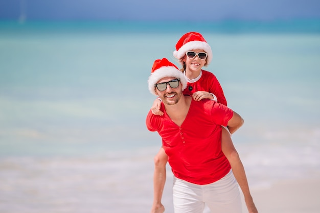 산타 모자에 아버지와 딸 열 대 해변에서 즐거운 시간을