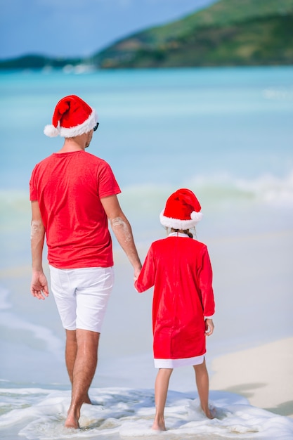 Father and daughter in Santa Hat have fun at tropical beach