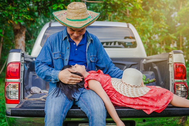 Father and daughter sit in the back of a pickup truck