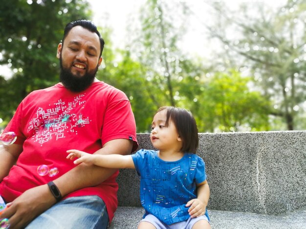 Photo father and daughter sitting in park