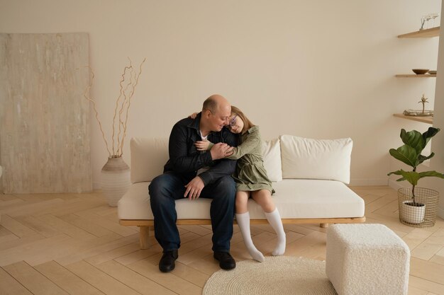 Father and daughter sitting on sofa in living room at home