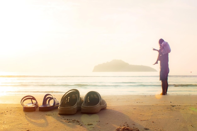 Father and daughter take off their sandals and lay on the beach\
daughter rides father\'s neck for a morning walk