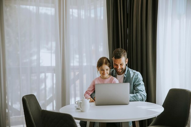 Father and daughter using laptop computer together in the room