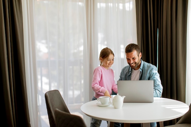 Father and daughter using laptop computer together in the room