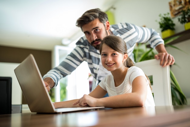  father and daughter using laptop in the living room