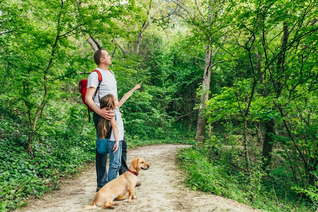 Padre e figlia che camminano attraverso i boschi con il cane