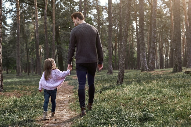 Padre e figlia che camminano insieme nella foresta, giorno d'autunno. bambina e suo padre che esplorano la natura all'aperto. fogliame autunnale colorato. retrovisore