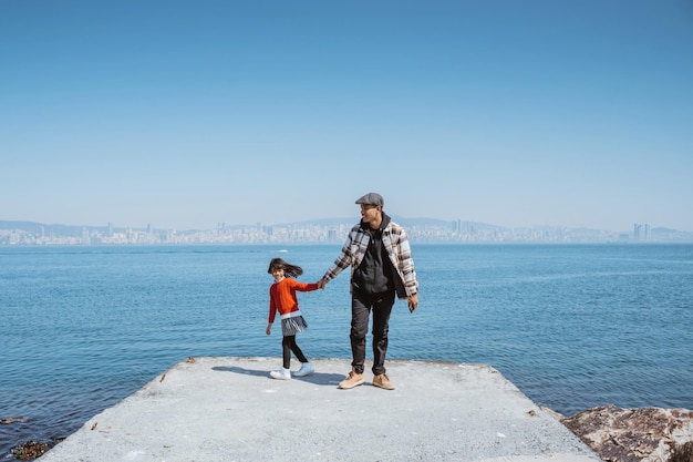 Отец и дочь гуляют вместе на причале рядом с Мраморным морем в чистом голубом небе